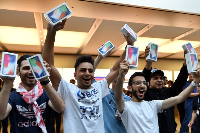 The first customers at an Apple showroom in Sydney display their iPhone X purchases