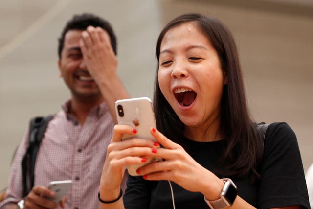 People try the Animoji feature on iPhone X during its launch at an Apple store in Singapore