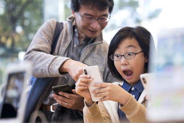 A girl reacts as she tries an iPhone X at the Apple Omotesando store on November 3, 2017 in Tokyo, Japan