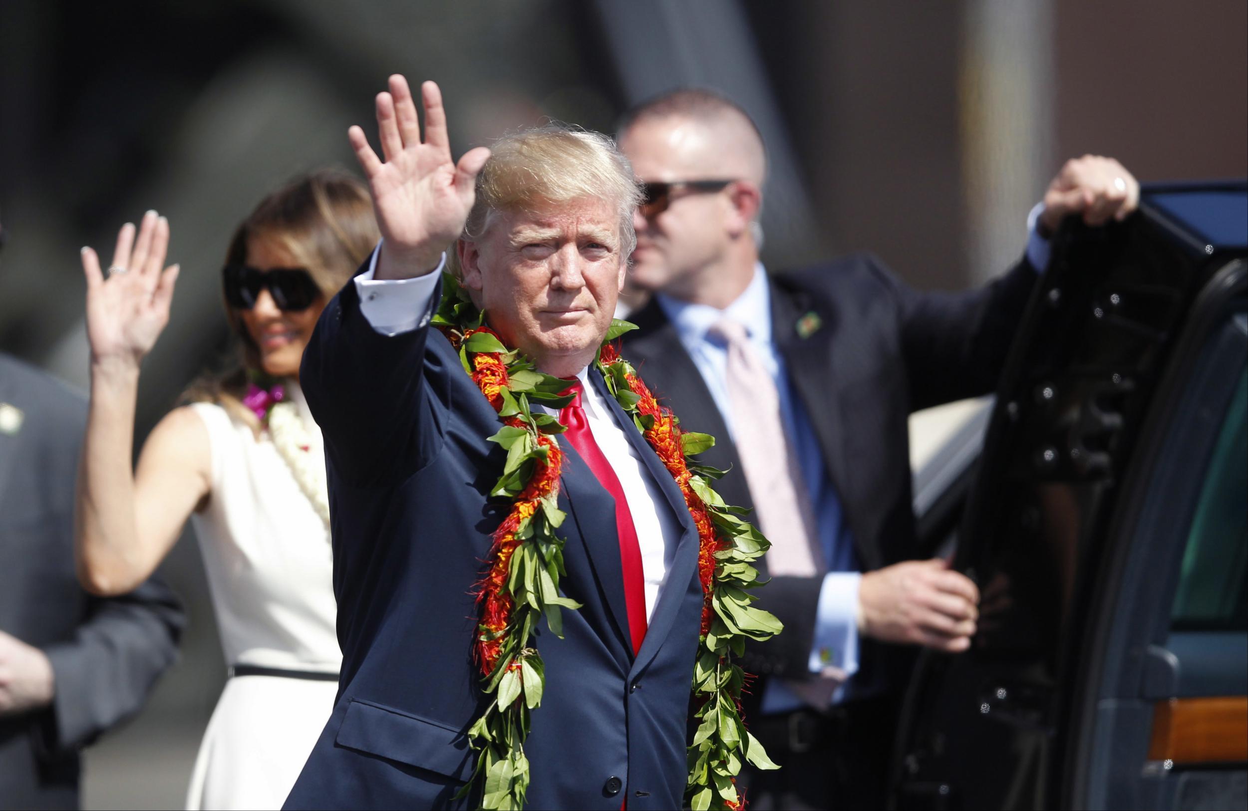 Adorned with lei, President Donald Trump walks towards the motorcade with first lady Melania Trump in Honolulu