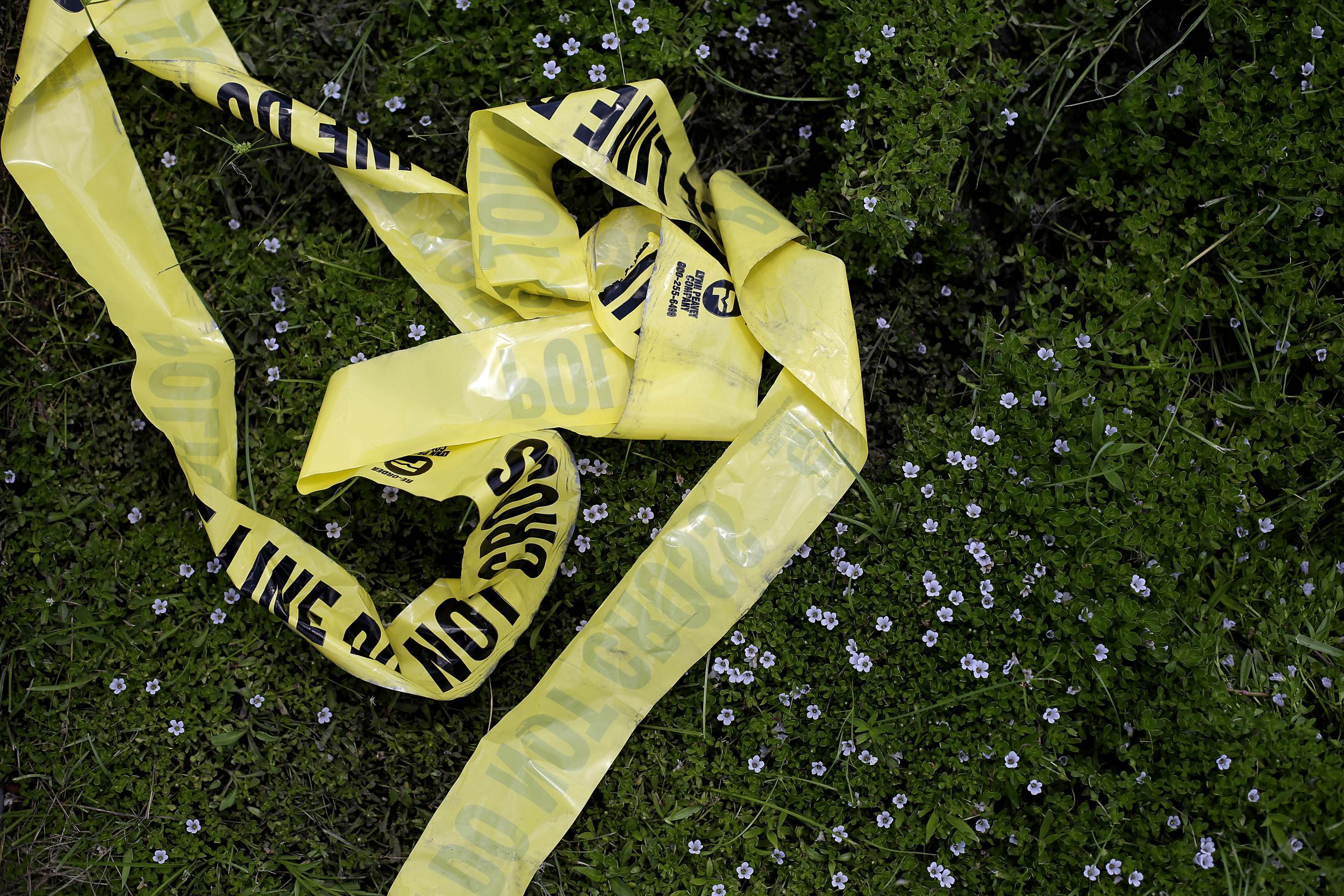 Yellow police crime scene tape rests in the grass in Baton Rouge, Louisiana after an unrelated crime