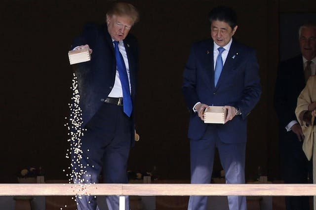 U.S. President Donald Trump, center, and Japan's Prime Minister Shinzo Abe, center right, feed carps before their working lunch at Akasaka Palace in Tokyo, Japan Monday, Nov. 6, 2017.