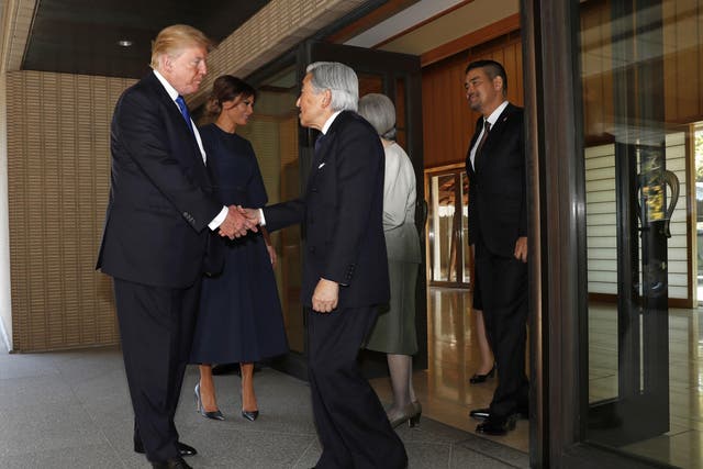 Donald Trump shakes hands with Japan's Emperor Akhito as first lady Melania Trump speaks to Empress Michiko