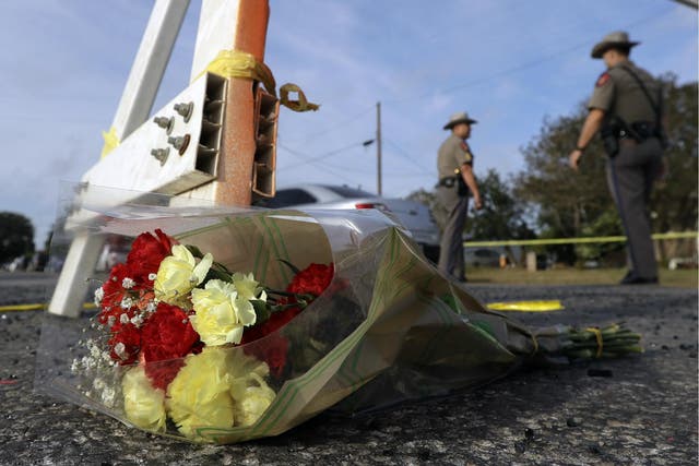 A bouquet of flowers lies at the base of a roadblock where law enforcement officials work at the scene of a shooting at the First Baptist Church of Sutherland Springs, 6 November 2017.