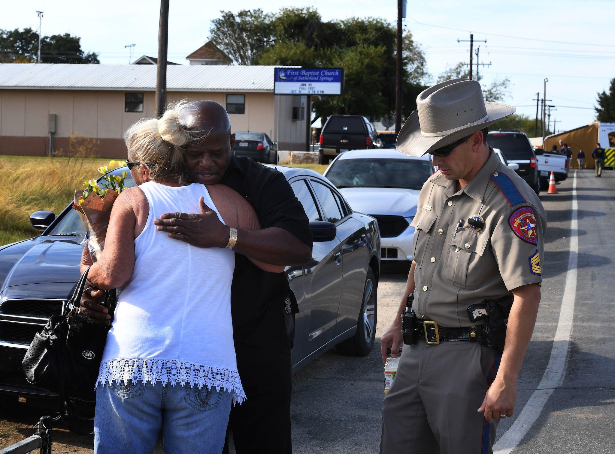 Local resident Jamie Rose is hugged by church member Raymond Antonio as she delivers flowers, at the entrance to the First Baptist Church after a mass shooting that killed 26 people in Sutherland Springs, Texas (MARK RALSTON/AFP/Getty Images)