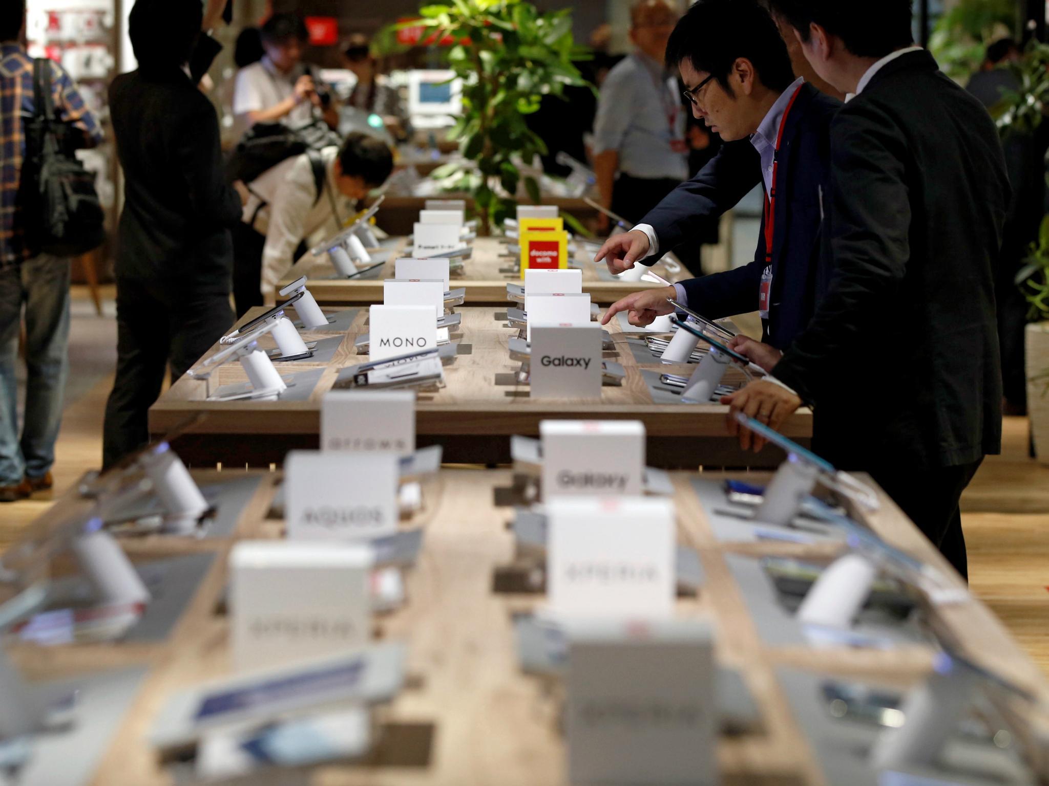 Visitors touch mobile phones at NTT Docomo's flagship shop in Tokyo, Japan June 30, 2017