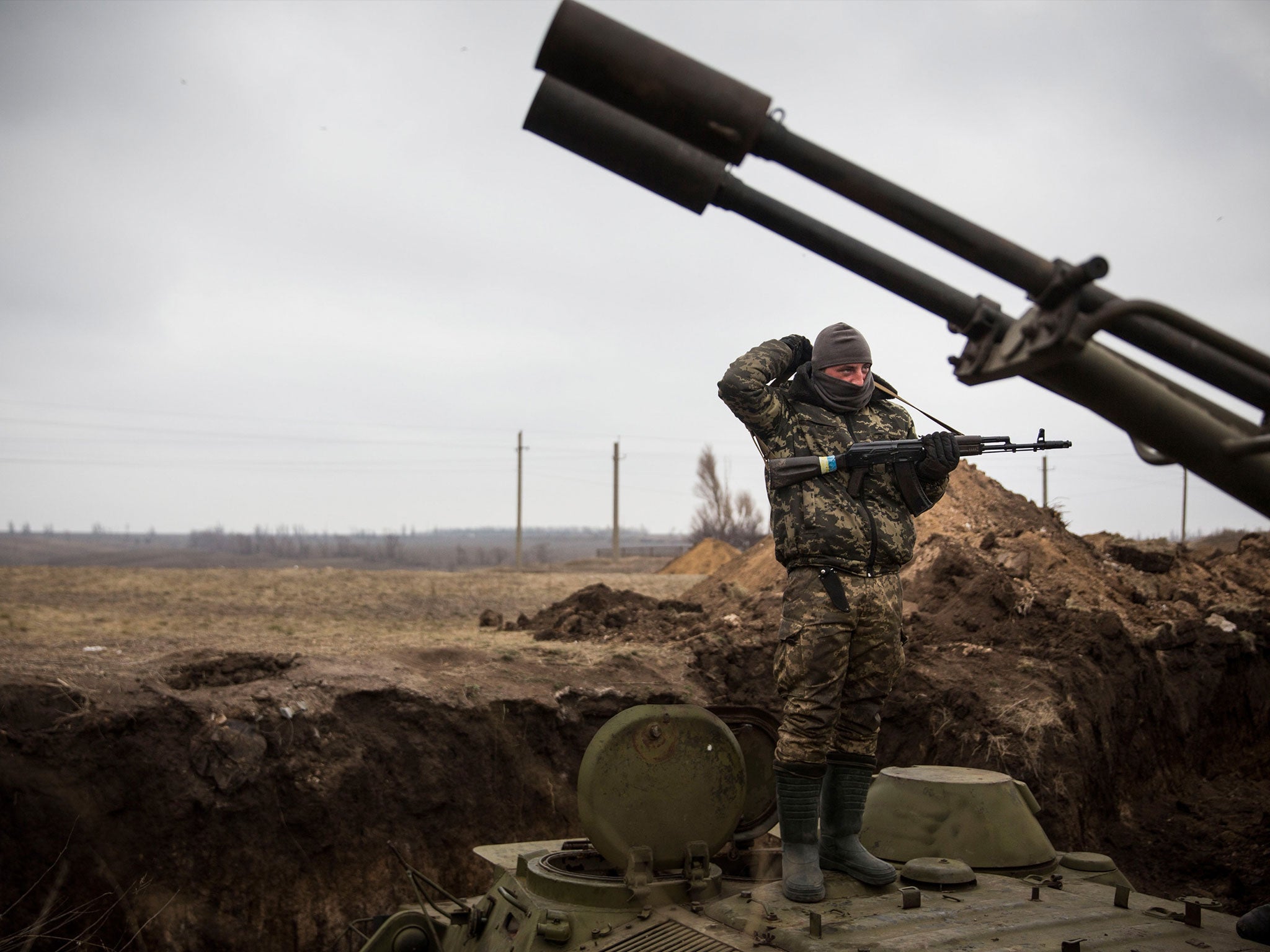 A Ukrainian soldier stands on top of an armored personal carrier in a trench