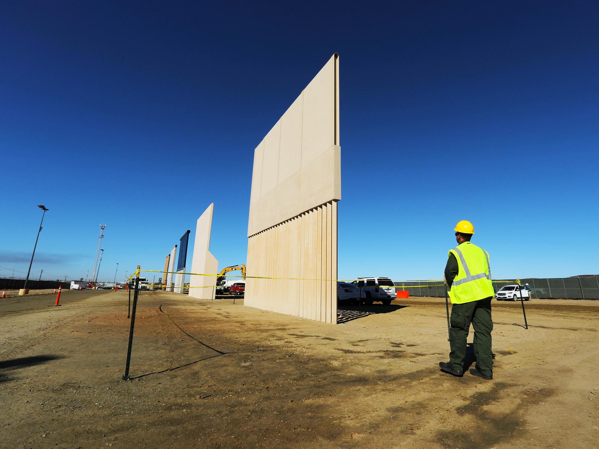 Border wall prototypes are shown near completion along the US-Mexico border in San Diego