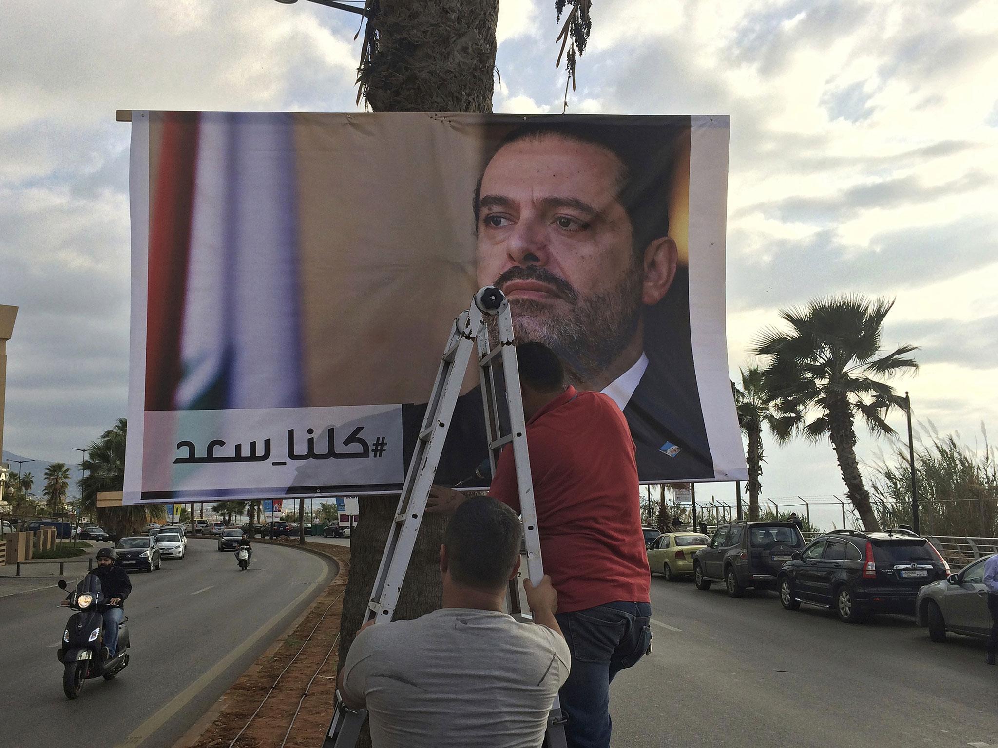 Workers in Beirut hang a poster of Prime Minister Saad Hariri with the message, ‘We are all Saad’