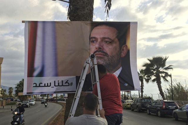 Workers in Beirut hang a poster of outgoing Prime Minister Saad Hariri with Arabic words that read, 'We are all Saad'