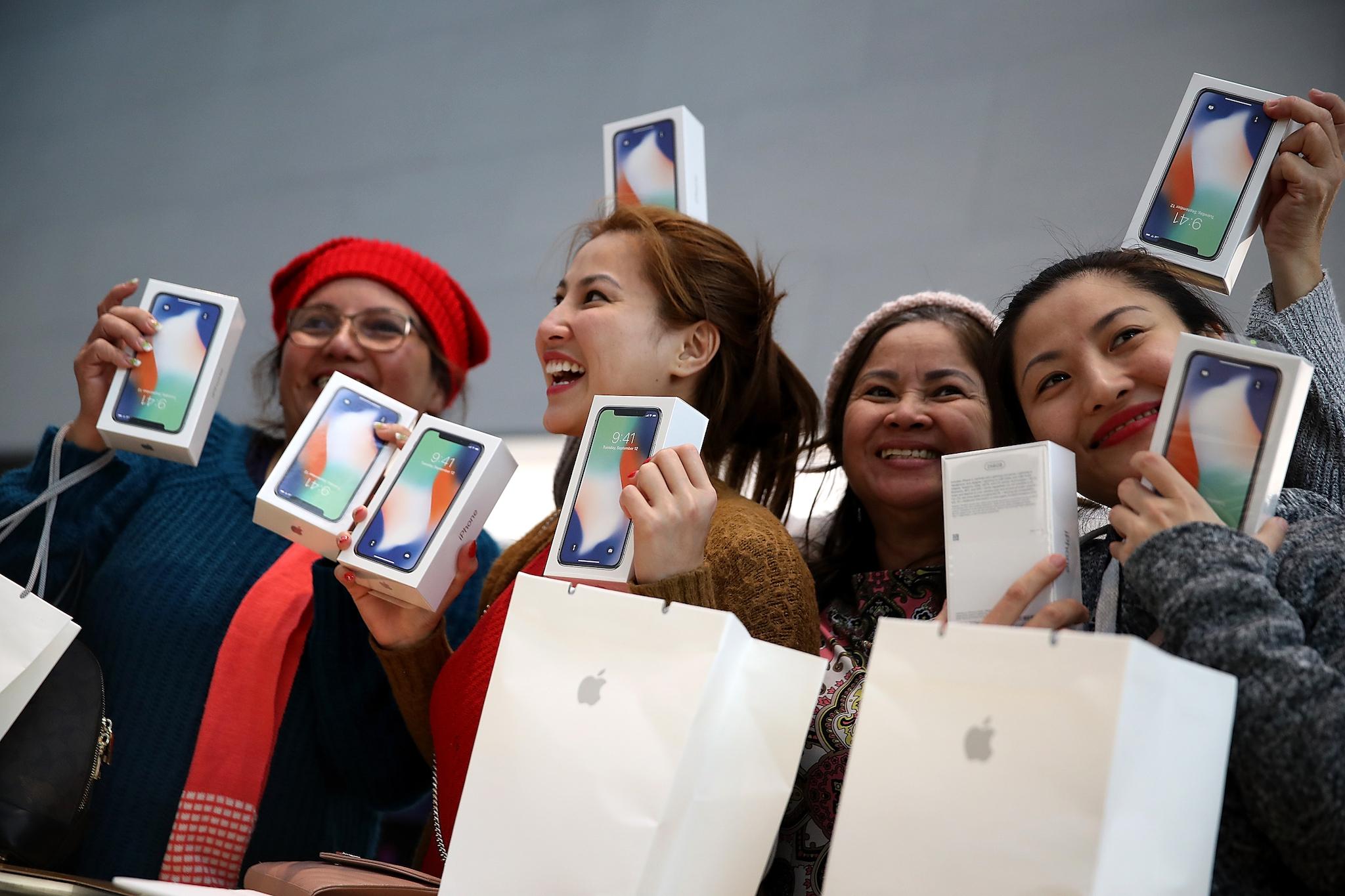 Customers hold up the new iPhone X at an Apple Store on November 3, 2017 in Palo Alto, California