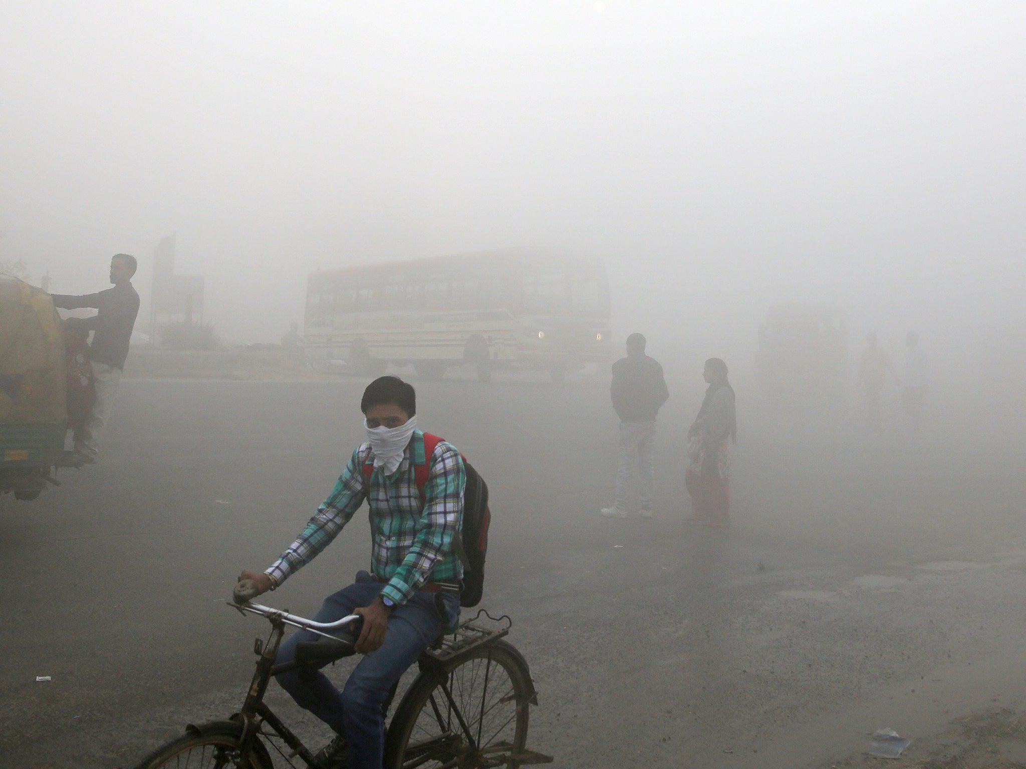 Indian commuters wait for transport amid a thick blanket of smog on the outskirts of New Delhi