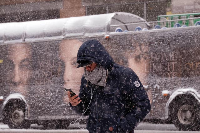 A man uses his smartphone as he crosses a street during a winter storm in New York on March 5, 2015