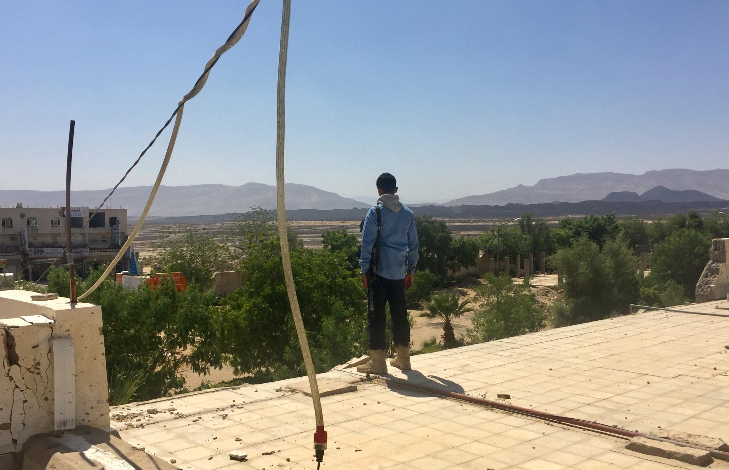 A government allied soldier looks towards Houthi-controlled mountains from the damaged roof of Marib’s General Hospital (Bethan McKernan)