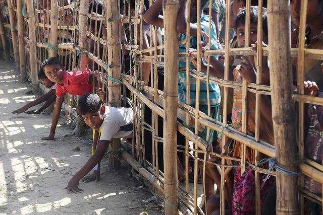 Young Rohingya refugees trying to climb through a temporary bamboo fence as they try to collect food at a camp in Bangladesh
