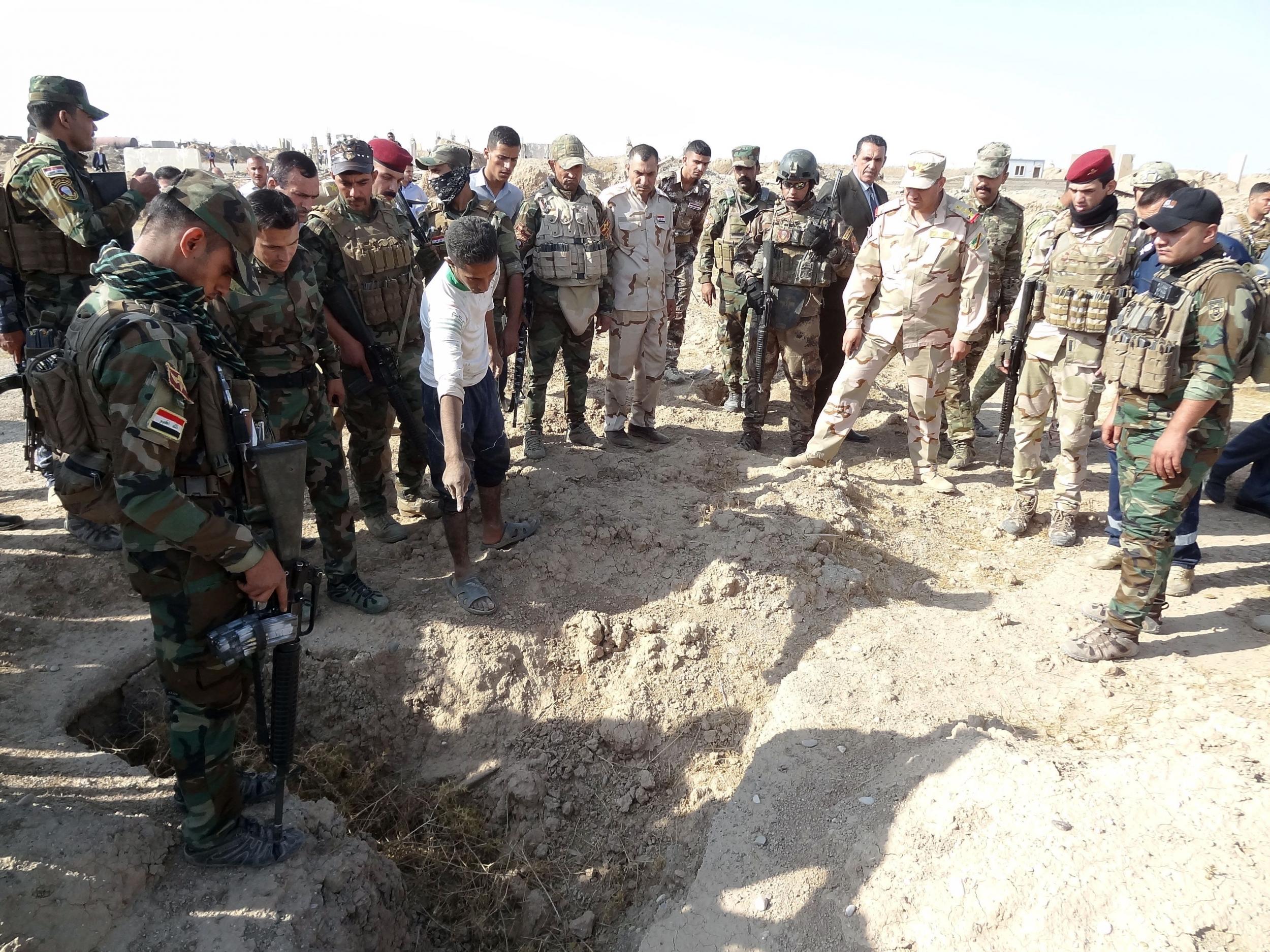 Iraqi forces search the site of a suspected mass grave containing the remains of victims of Isis, near the former al Bakara military base, on 11 November 2017