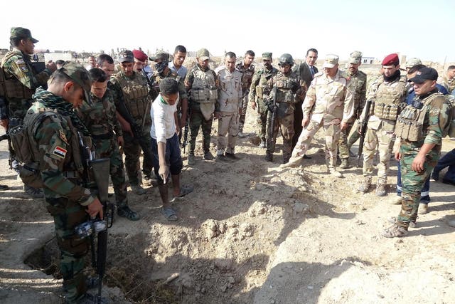 Iraqi forces search the site of a suspected mass grave containing the remains of victims of Isis, near the former al Bakara military base, on 11 November 2017