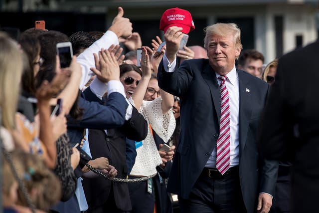 President Donald Trump holds up a 'Make America Great Again' hat