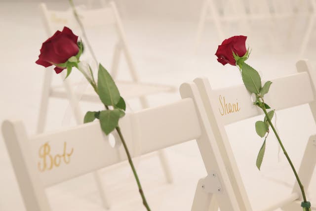 On each chair is a single rose and the name of a shooting victim