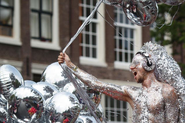 A reveler on a boat covered in glitters parades the Prinsengracht canal participating in the Amsterdam Canal Parade during Amsterdam Gay Pride.