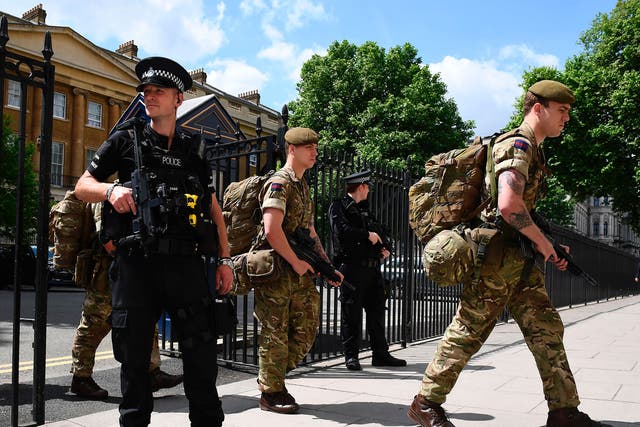 Ministry of Defence Police officers on guard as soldiers enter a building in central London on 24 May 2017