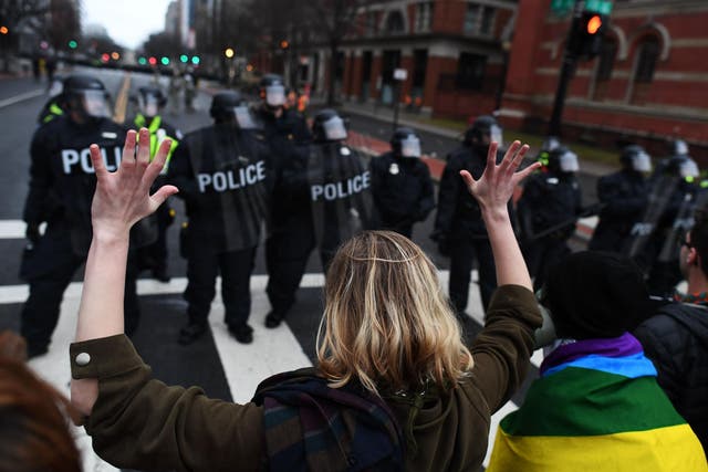 An anti-Trump protester holds her hands up as police officers lineup in Washington, DC,