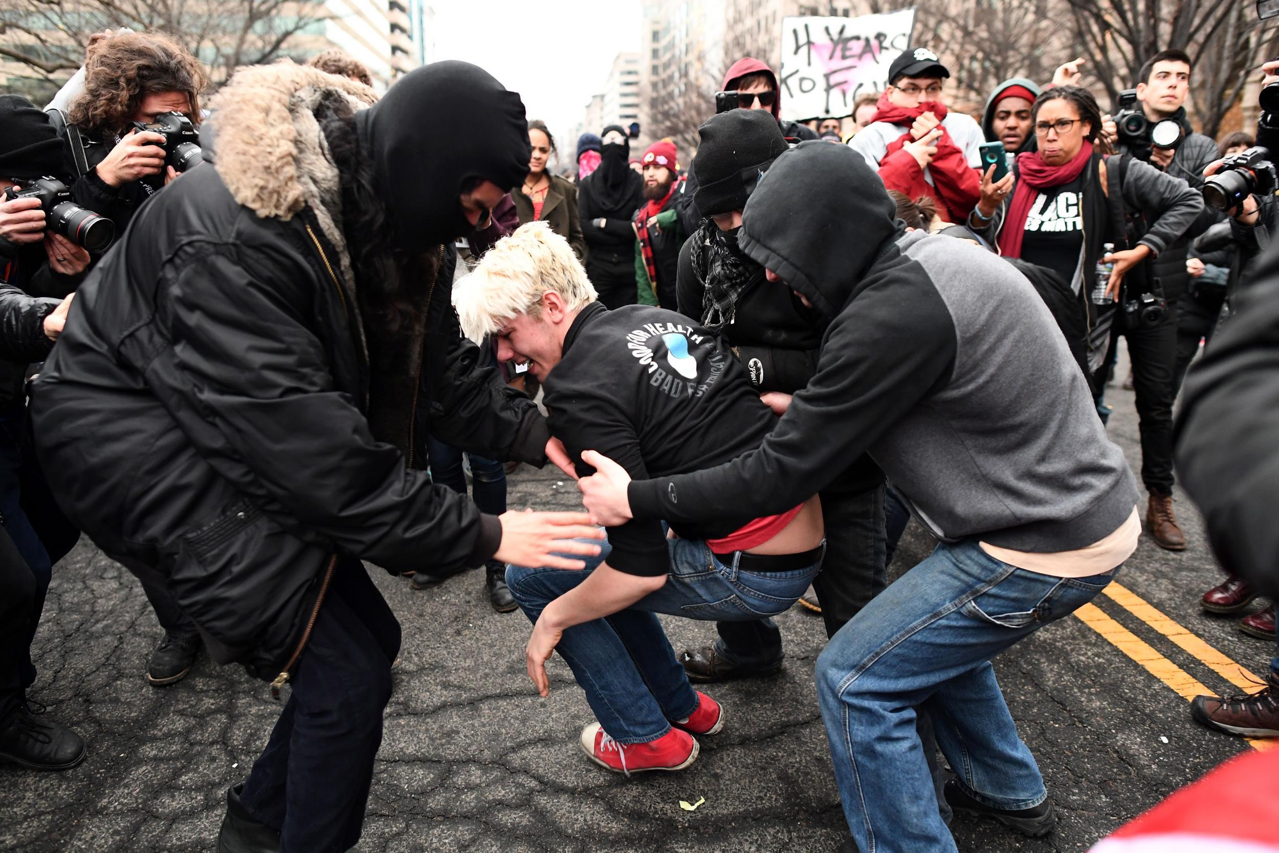 An anti-Trump protester screams after being hit by a paintball gun fired by Police during clashes in Washington, DC