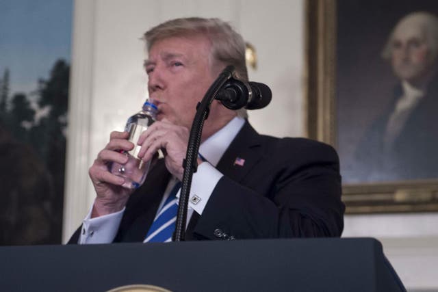 President Donald Trump drinks water from a bottle as he delivers a speech on his Asia trip
