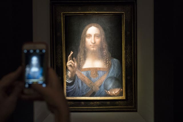 People take pictures of the painting 'Salvator Mundi' by Leonardo da Vinci
