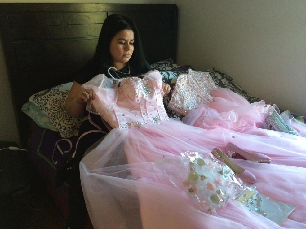 Maria Reyes holds a dress her daughter Damaris was going to wear for a Sweet 15 Quinceanera celebration