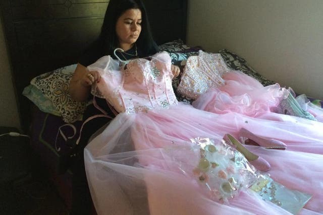 Maria Reyes holds a dress her daughter Damaris was going to wear for a Sweet 15 Quinceanera celebration