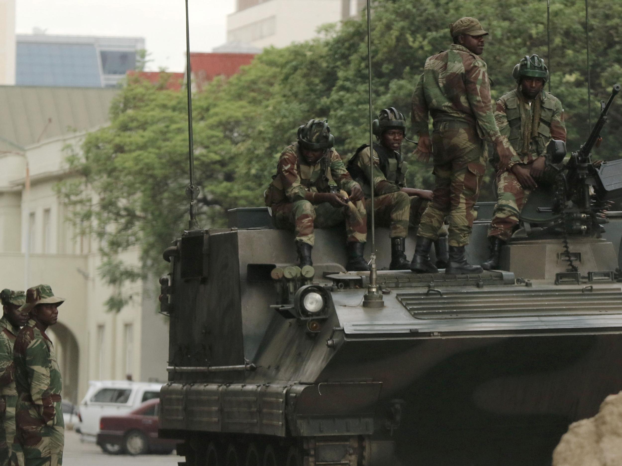 Soldiers are seen next to and on the armoured vehicle on the street in central Harare