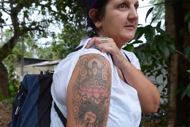 British tourist Naomi Coleman poses for a photograph to display a tattoo of the Buddha on her upper arm, after she was arrested at Sri Lanka's main international airport in 2014