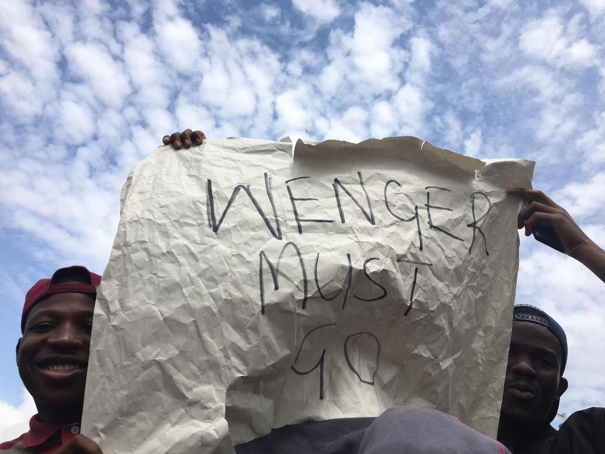 Protesters at a demonstration against Robert Mugabe hold a sign calling for Arsenal manager Arsene Wenger’s removal