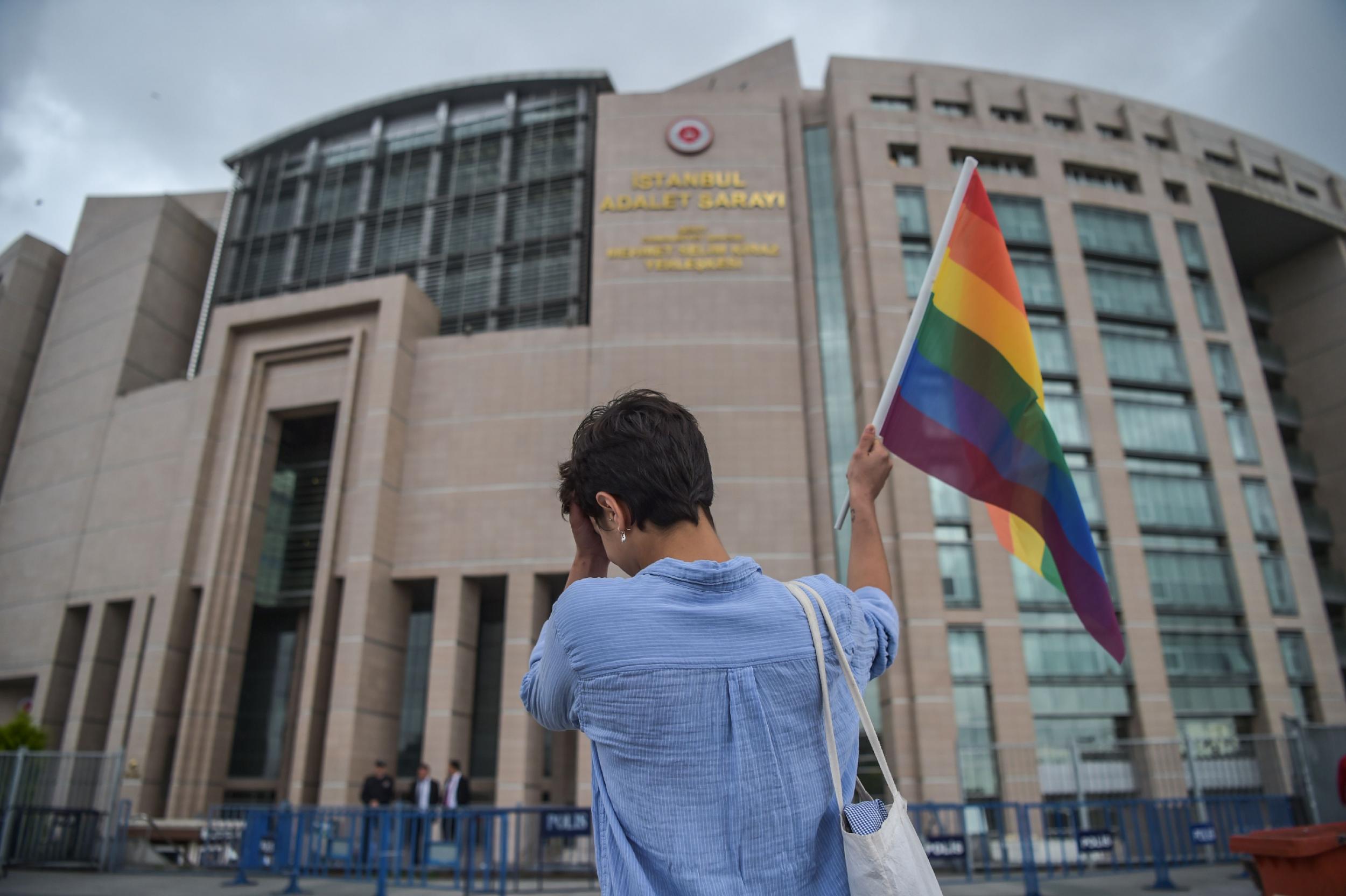 A person waves a rainbow flag in front of Istanbul courthouse in support of eleven LGBTI activists charged with attending last year's banned gay pride march