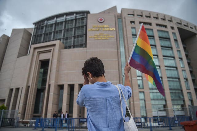 A person waves a rainbow flag in front of Istanbul courthouse in support of eleven LGBTI activists charged with attending last year's banned gay pride march