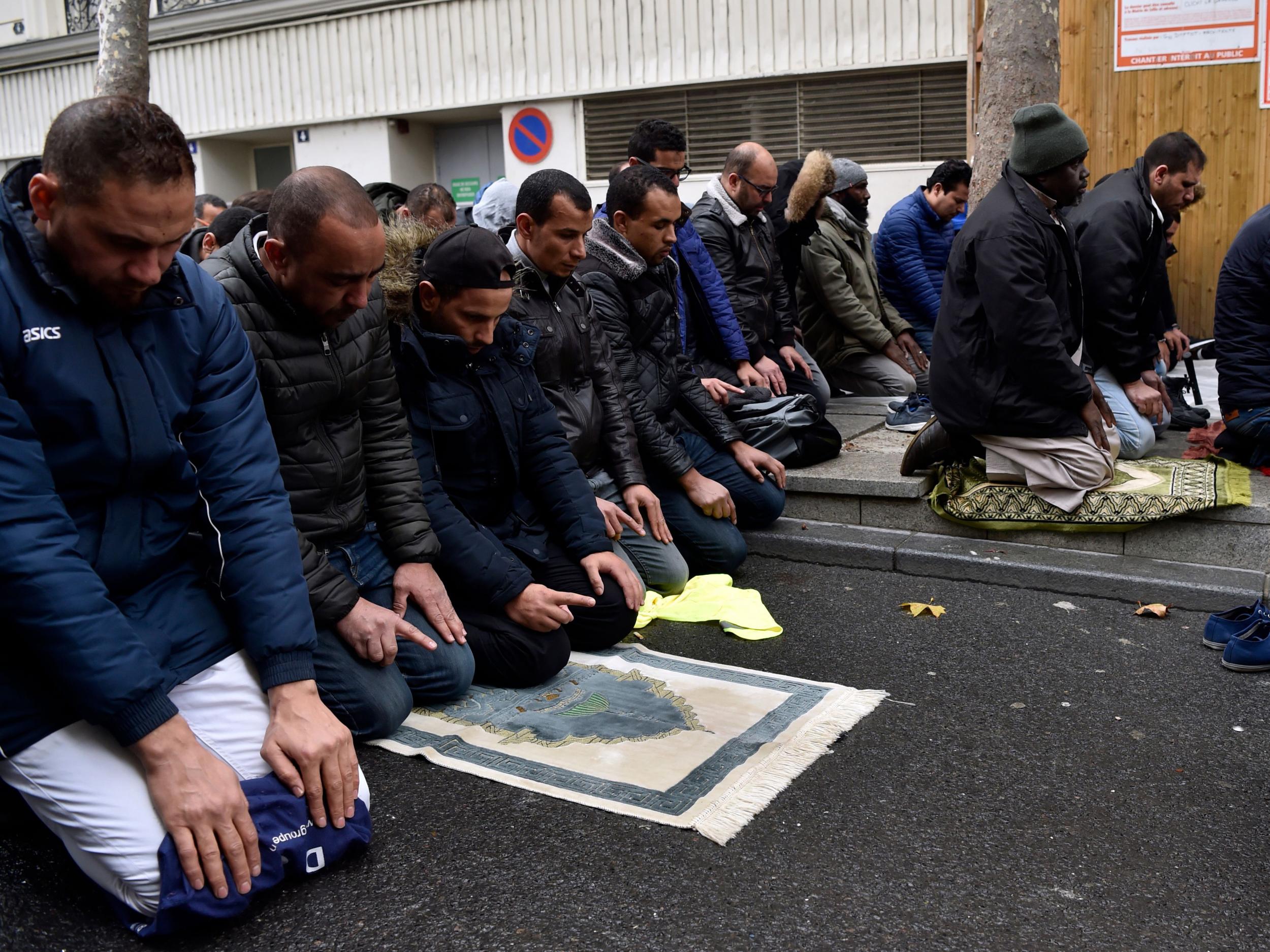 People pray in a street on 10 November in Clichy, near Paris, while the city mayor demonstrate with others political leaders against Muslim streets prayers