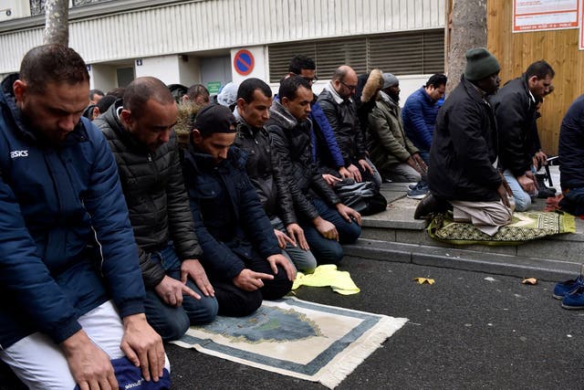 People pray in a street on 10 November  in Clichy, near Paris, while the city mayor demonstrate with others political leaders against Muslim streets prayers