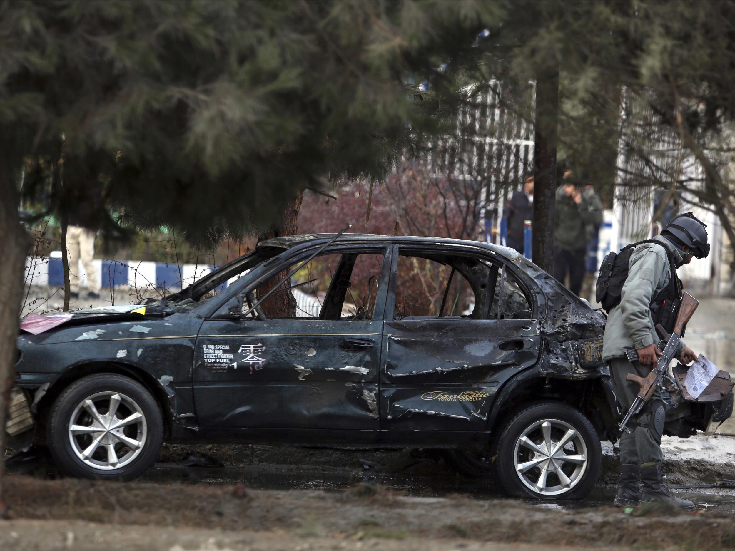 An Afghan security personnel inspects the site of a deadly suicide bombing in Kabul