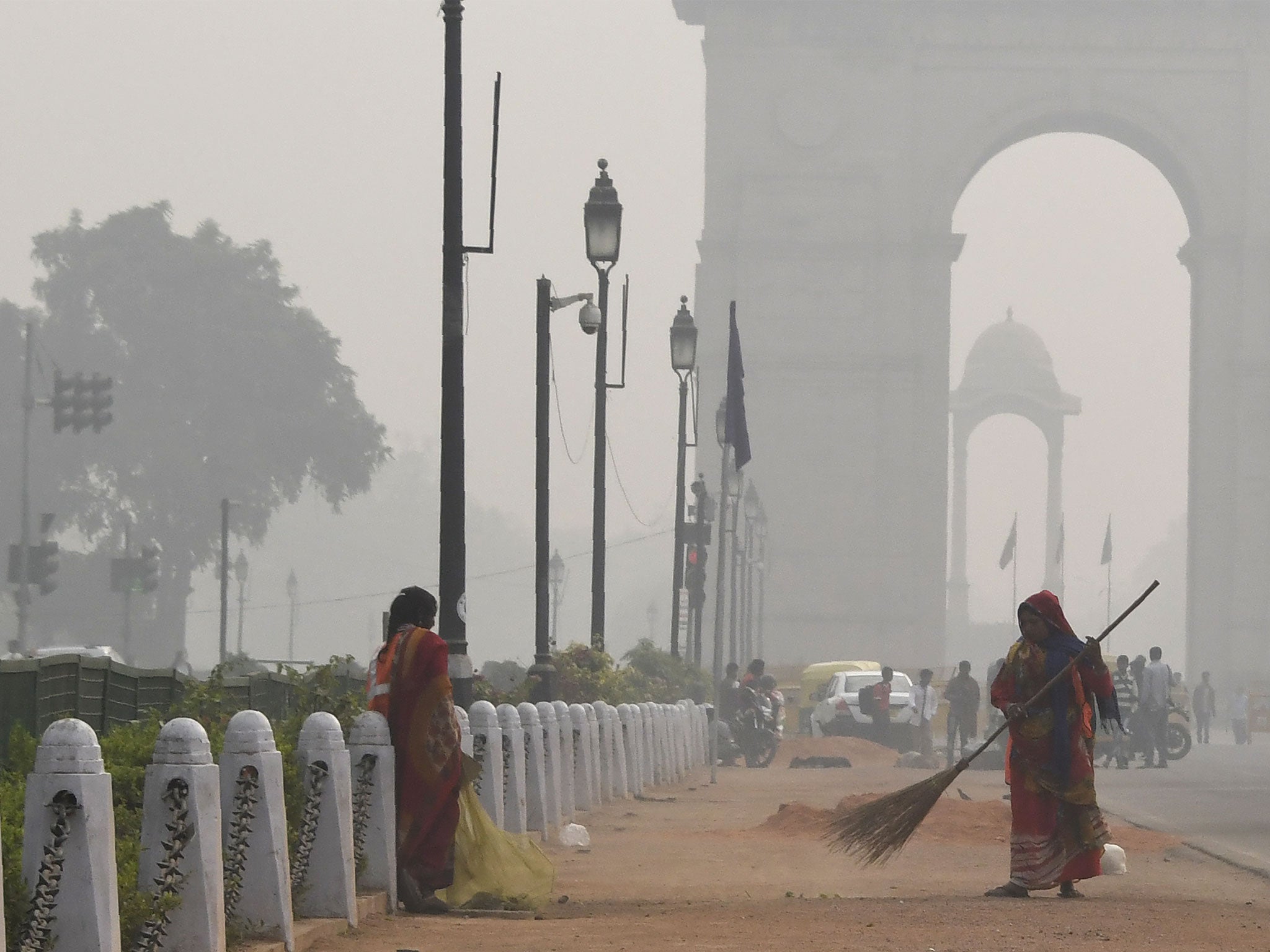 A woman cleans a road amid heavy smog near India Gate, New Delhi, in November