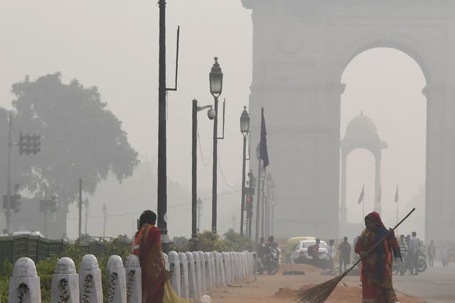 A woman cleans a road amid heavy smog near India Gate, New Delhi, in November
