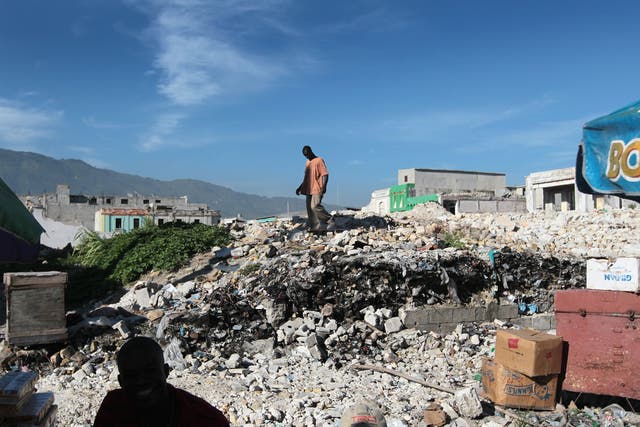 People examine a collapsed building after the 2010 earthquake. Advocates for Haitians say conditions in the island nation haven't improved nearly enough for Haitians to be deported.