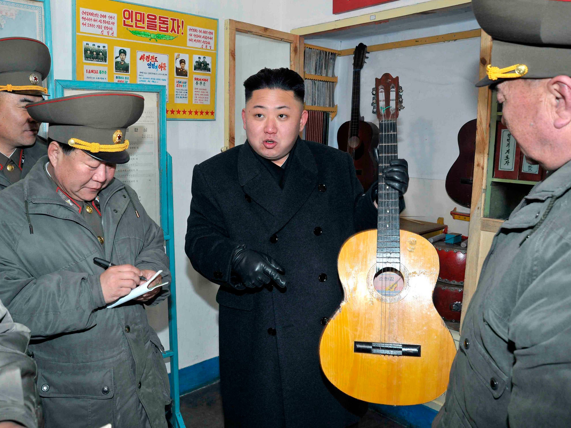 North Korean leader Kim Jong-Un holds a guitar during a visit to a military unit on the Wolnae Islet Defence Detachment in 2013