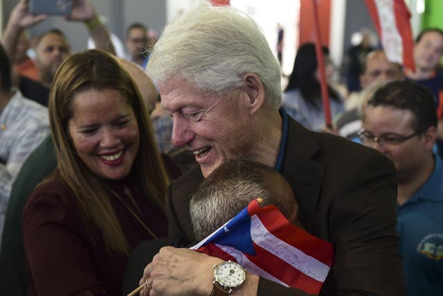 Former President Bill Clinton hugs a resident living at the William Rivera Betancourt Vocational School which was turned into an emergency shelter for families affected by the impact of Hurricane Maria