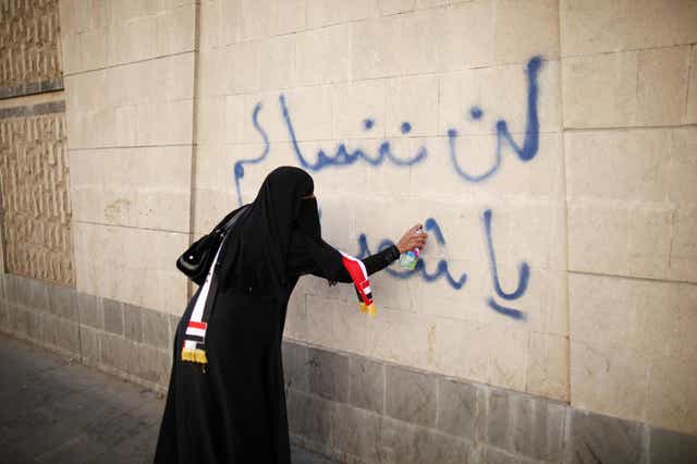 A woman writes 'We won't forget you, oh our martyrs' on a wall in Sanaa, Yemen during a 2013 protest demanding an end to the violence which consumed the country after the Arab Spring