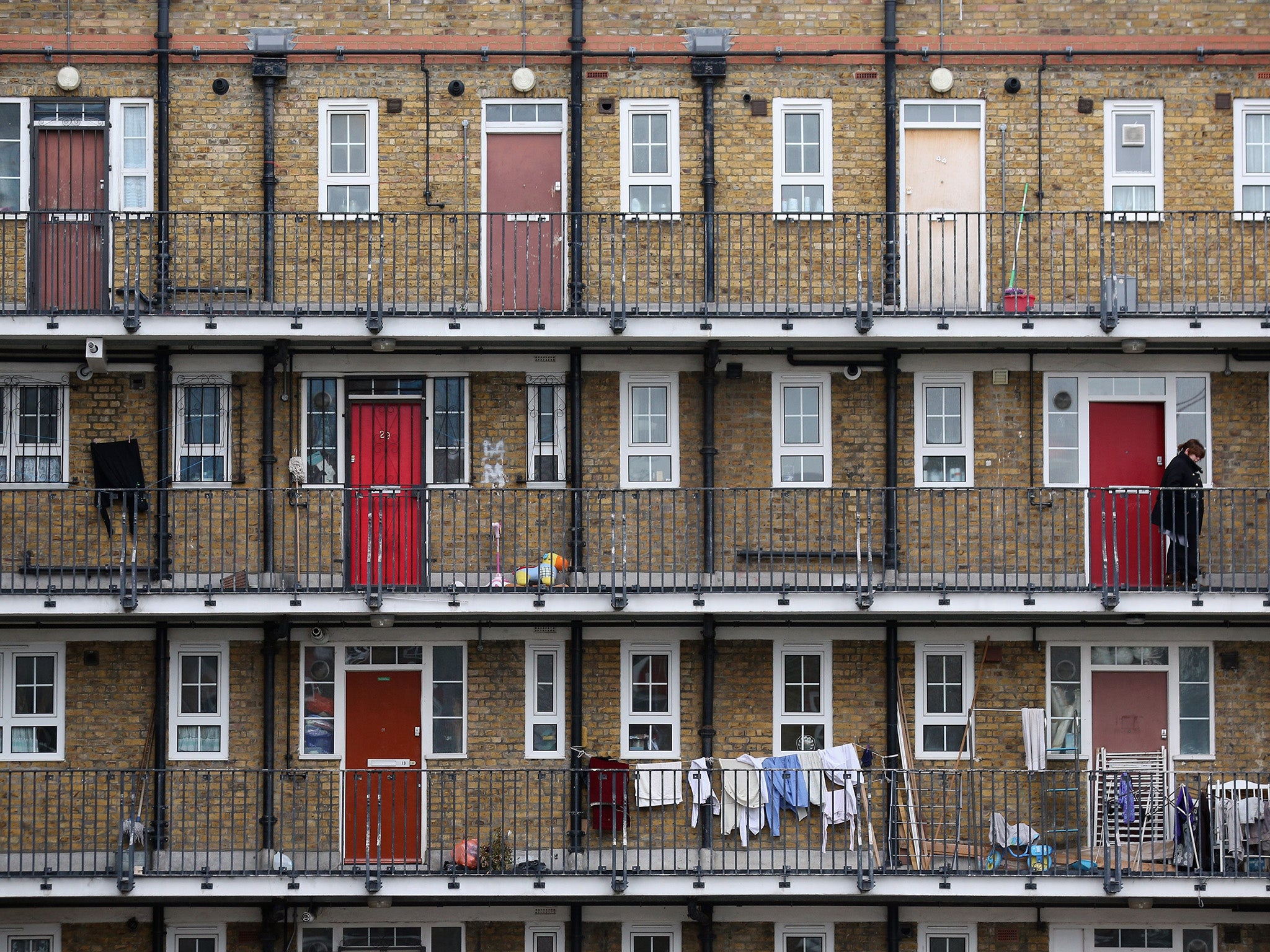 A woman looks out from a residential development in the London borough of Tower Hamlets