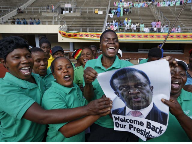 A band holds a picture of Emmerson Mnangagwa and sings as they await his arrival at the presidential inauguration ceremony