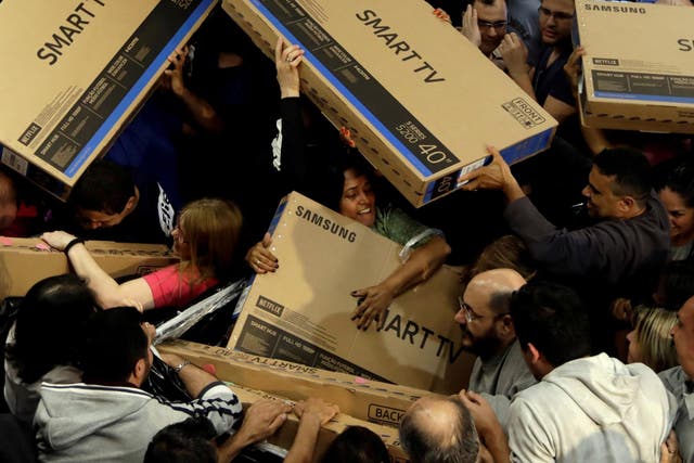 Shoppers reach out for television sets as they compete to purchase retail items on Black Friday at a store in Sao Paulo, Brazil
