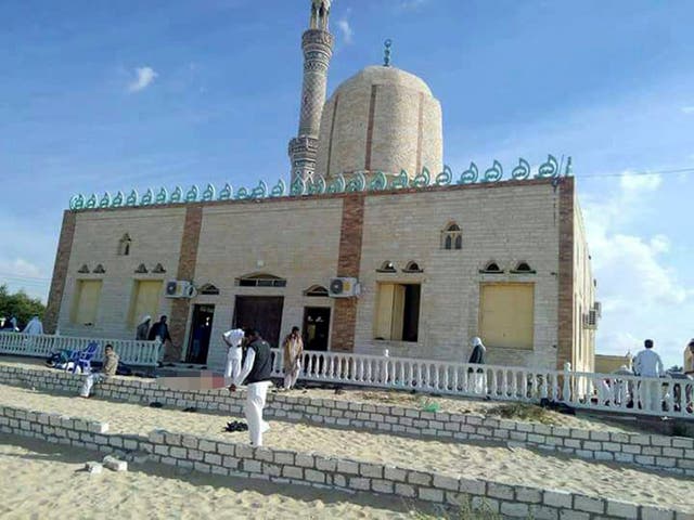 People walk outside a mosque that was attacked in the northern city of Arish, Sinai Peninsula