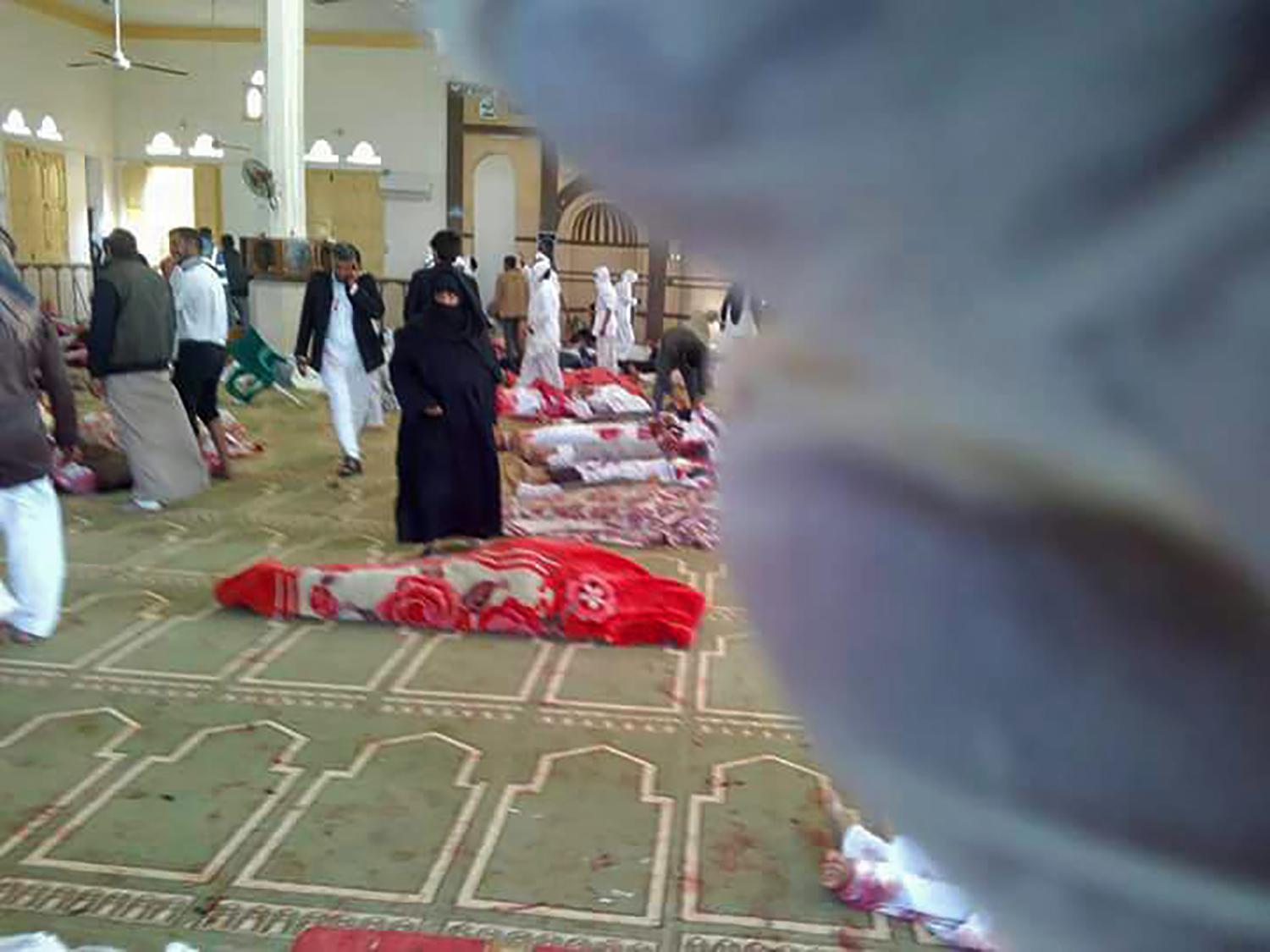 People gather around bodies after the attack at the al-Rawdah mosque, near the North Sinai capital of El-Arish on 24 November 2017